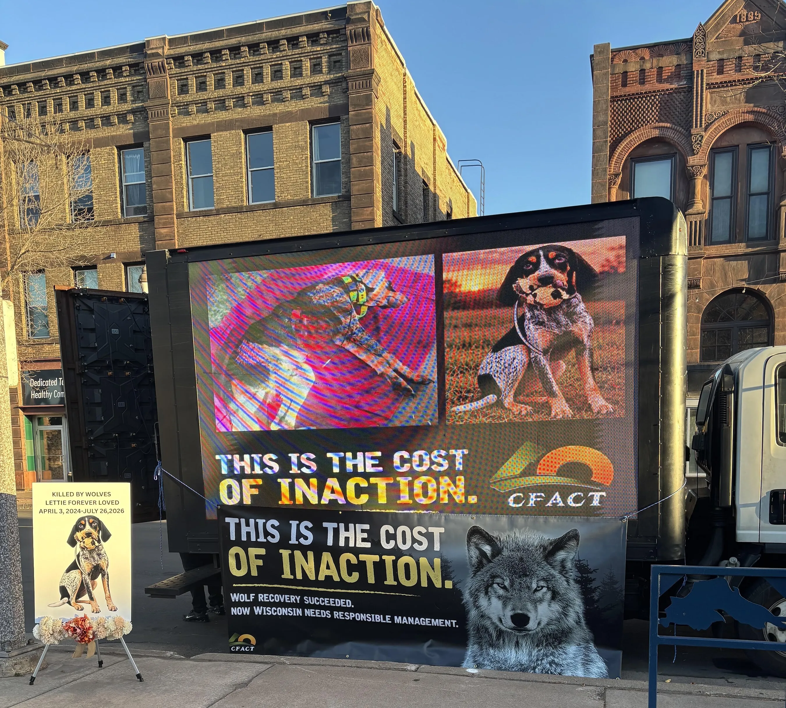 Digital billboard showing two dogs and the words “This is the cost of inaction.”